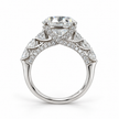 Make a statement from every angle. This engagement ring features a 5 carat round lab-grown center diamond framed by larger diamonds along the shoulders. Delicate diamonds beneath the center and along the sides of the band add detail to its striking profile. Crafted in 14K white gold, the ring has a total diamond weight of 6 5/8 carats.